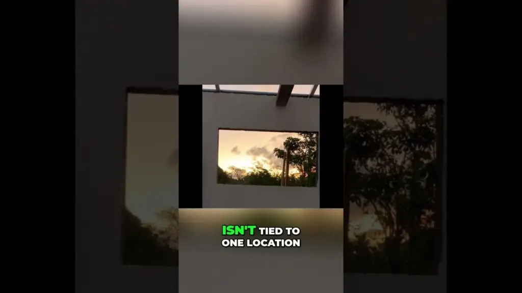 Square window opening in a white wall frames a sunset with trees outside; bold caption reads 'ISN'T TIED TO ONE LOCATION'