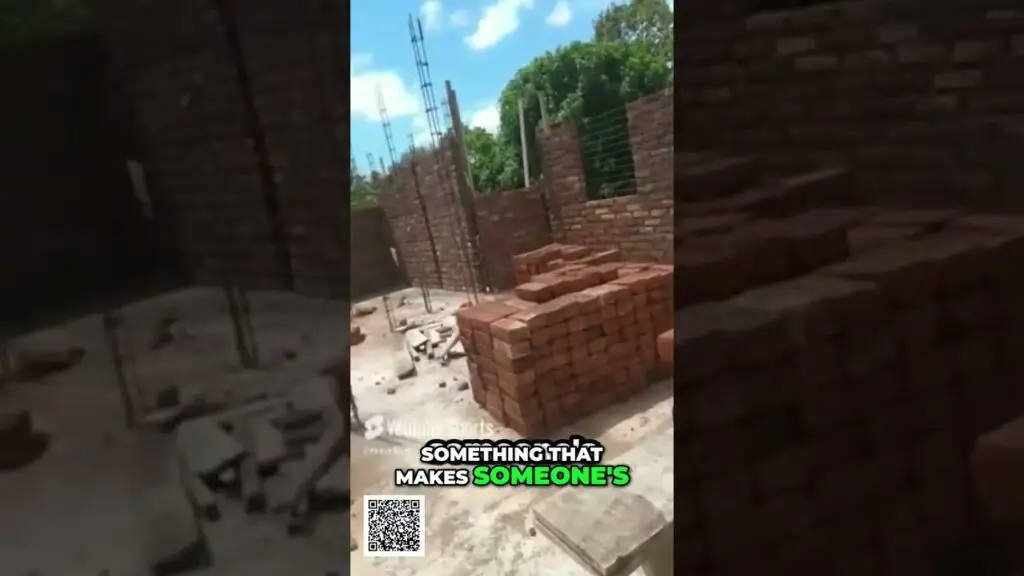 Construction site with stacked red bricks, a partially built brick wall, and metal reinforcement bars under a blue sky (video overlay text reads 'SOMETHING THAT MAKES SOMEONE'S').
