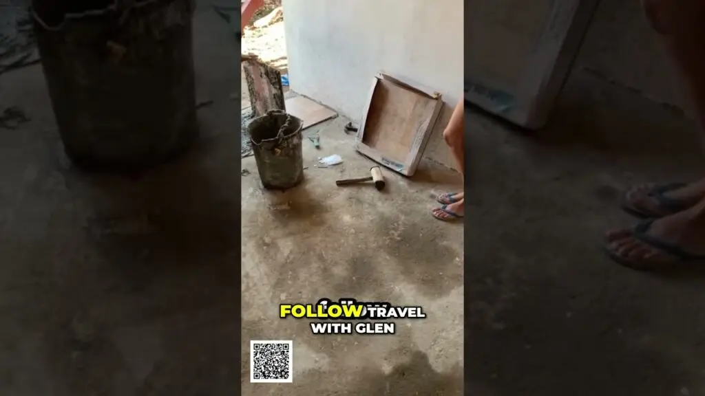 Airbnb Empire Building From Scratch in Nicaragua shorts - Travel With Glen Video thumbnail showing a dusty concrete floor with a rusty bucket, a hammer, and a wooden frame leaning against a wall; a person’s flip-flop-wearing feet visible; on-screen text reads 'FOLLOW TRAVEL WITH GLEN'.