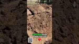 Dug trench in a dirt yard with piled soil; on-screen text reads “CONTROL OVER WHERE YOU LIVE” with a red heart and a QR code nearby.