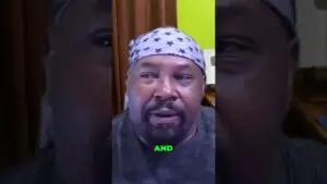 Close-up of a man wearing a star-pattern bandana, mid-speech, with a lime-green word 'AND' overlaid at the bottom.