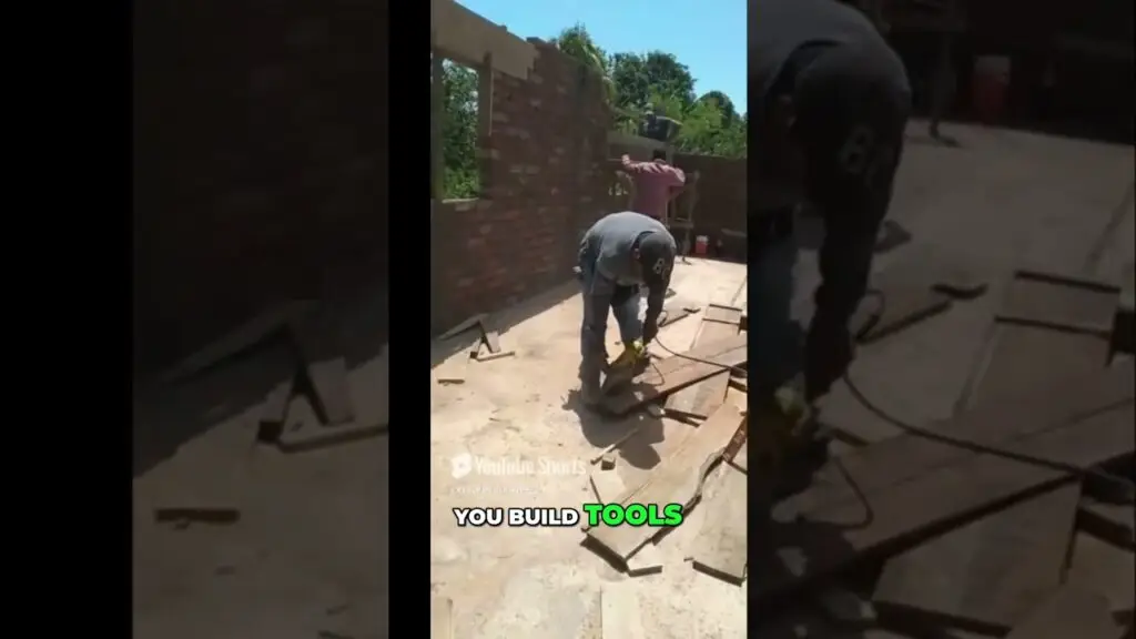 Man cutting wood with a power tool on a sunny construction site, a brick wall being built in the background.