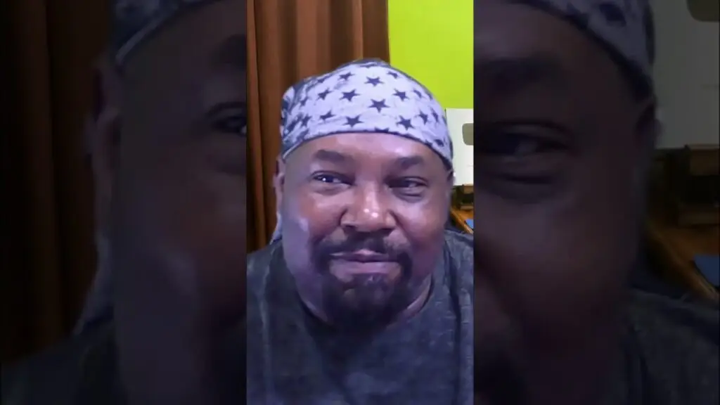Selfie of a man wearing a star-pattern bandana, smiling at the camera indoors.